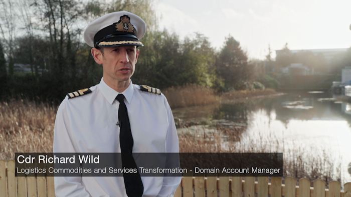 Commander Richard Wild in Naval uniform being interviewed with water behind him